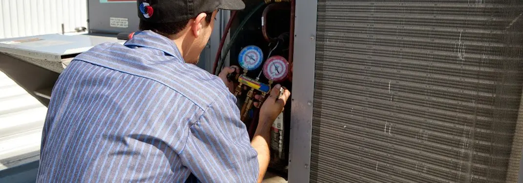 HVAC technician servicing a condenser unit in Colby